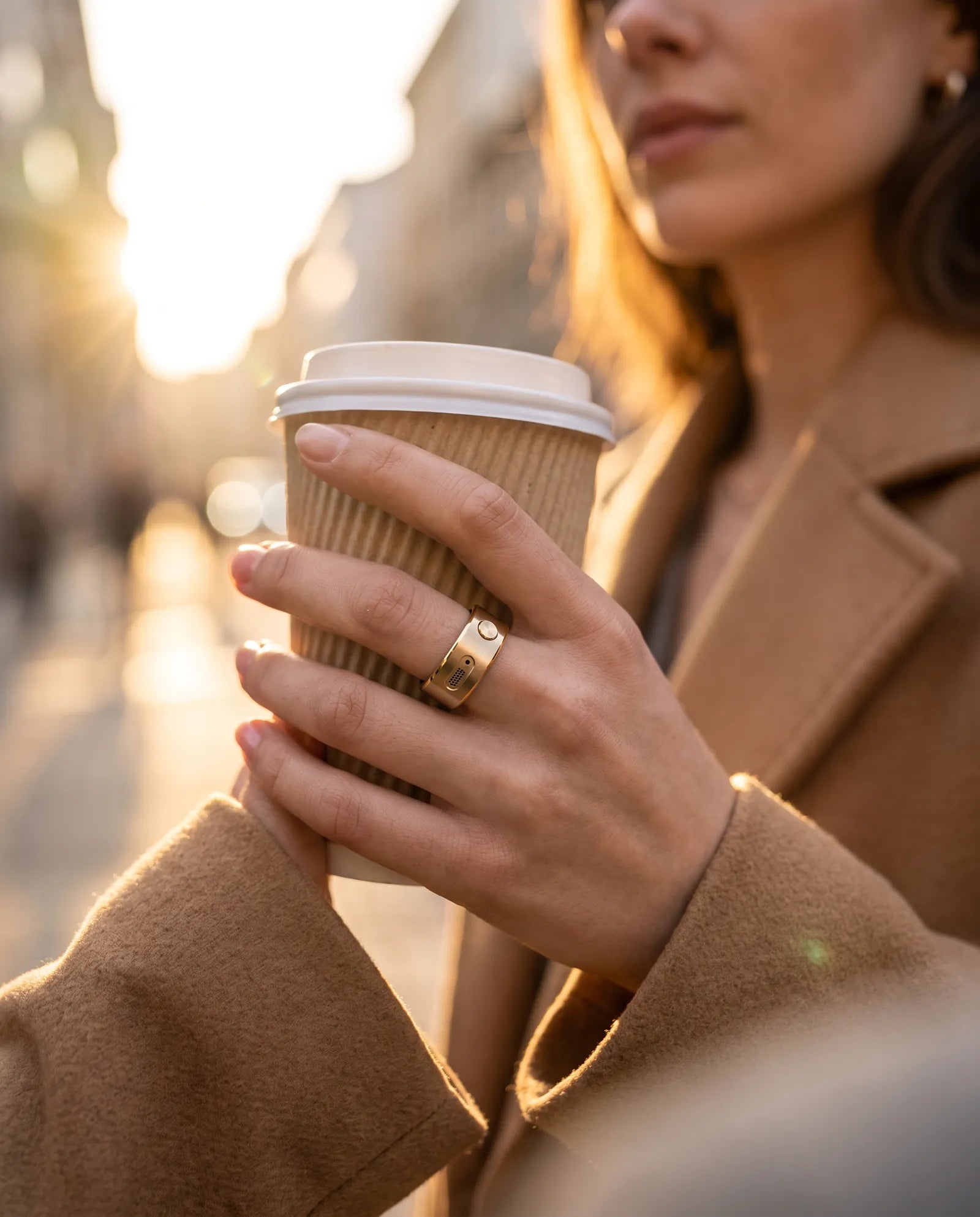 A woman holding coffee, wearing the gold ring