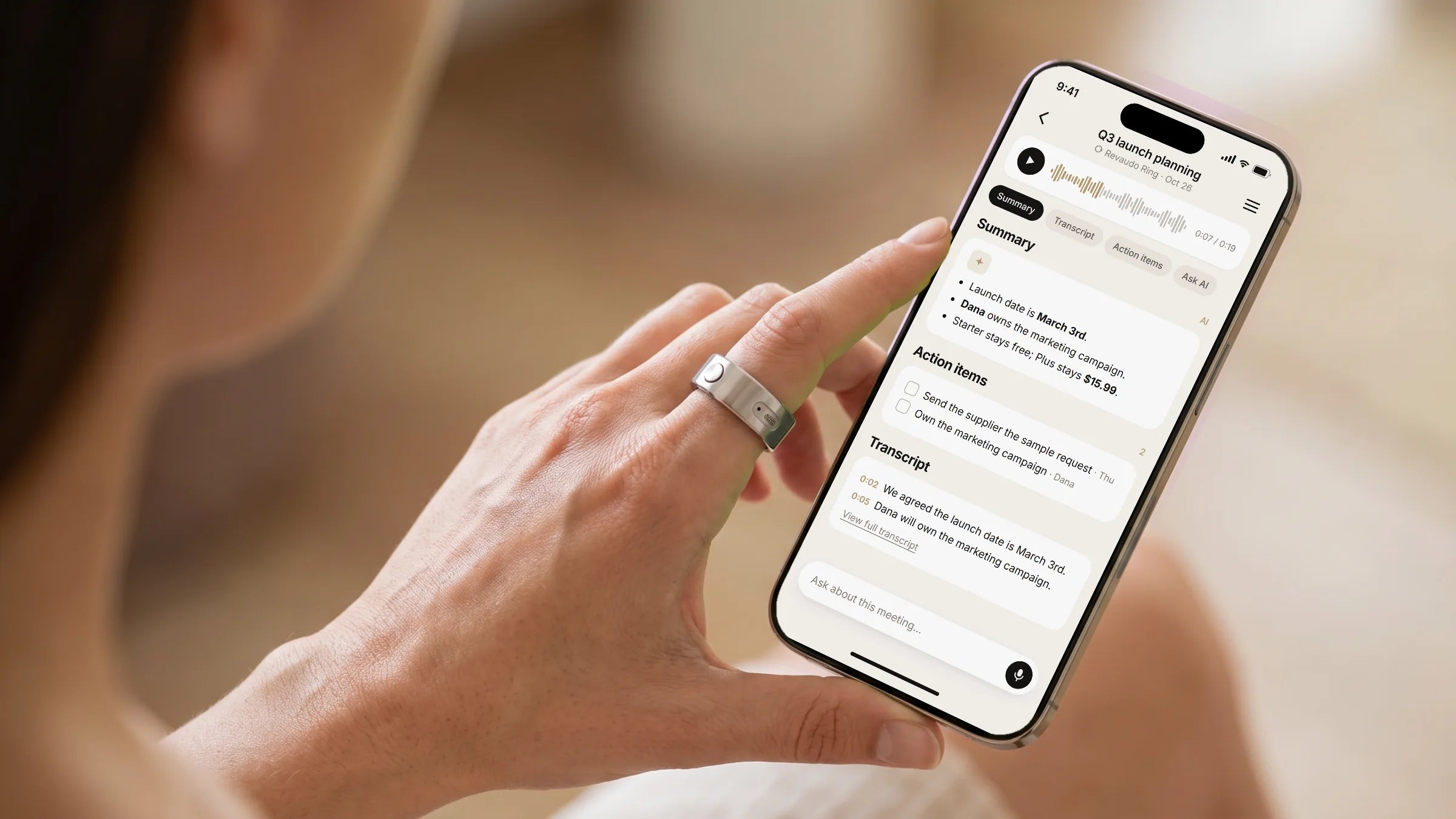 A hand holding a phone showing a meeting summary in the Revaudo app